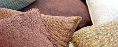 A collection of textured scatter cushions in various earthy tones, adding comfort and style to any seating arrangement.