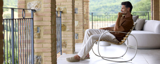 A person relaxes in a stylish rocking chair, enjoying the scenic view while seated comfortably.