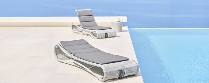 Modern grey and white lounge chairs beside a swimming pool.