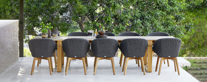 Modern outdoor dining set featuring black chairs and a wooden table.