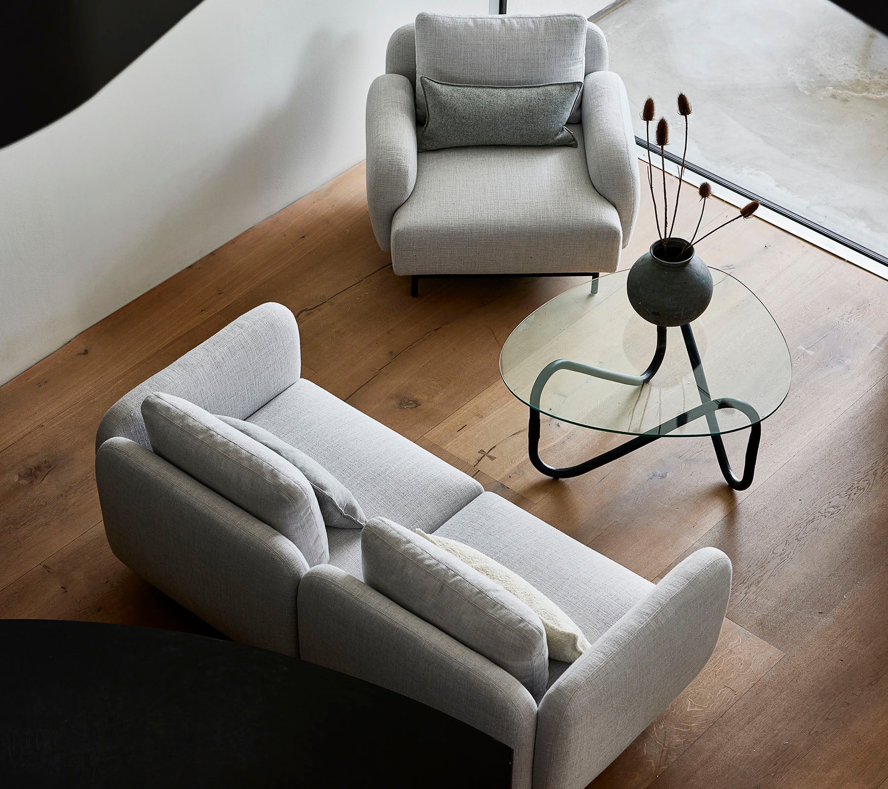 Stylish gray sofas and an elegant glass coffee table, featuring decorative elements on the tabletop, set against a warm wood floor.