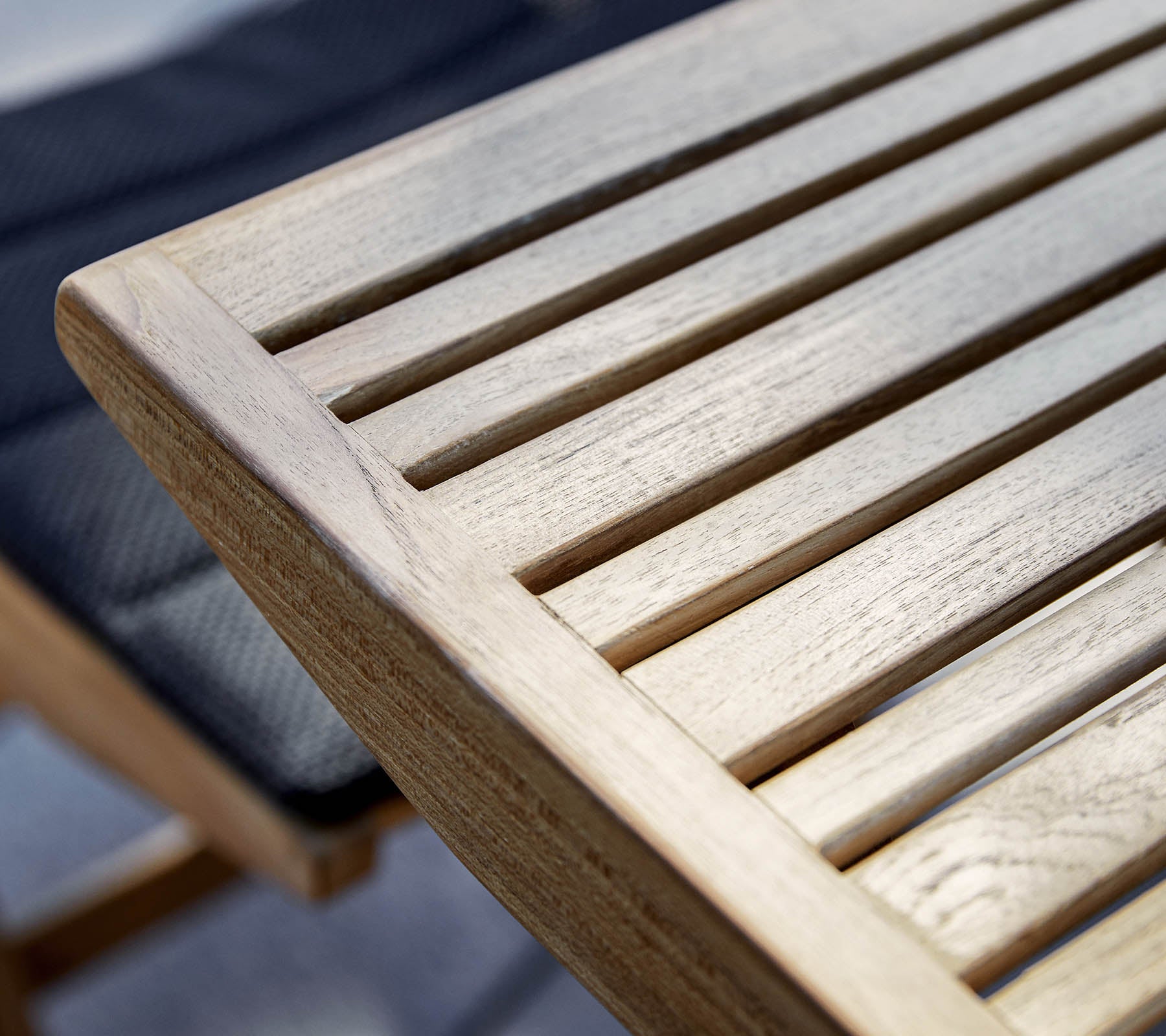 Close-up of a wooden table edge with slatted design, showcasing the natural grain and texture of the wood.