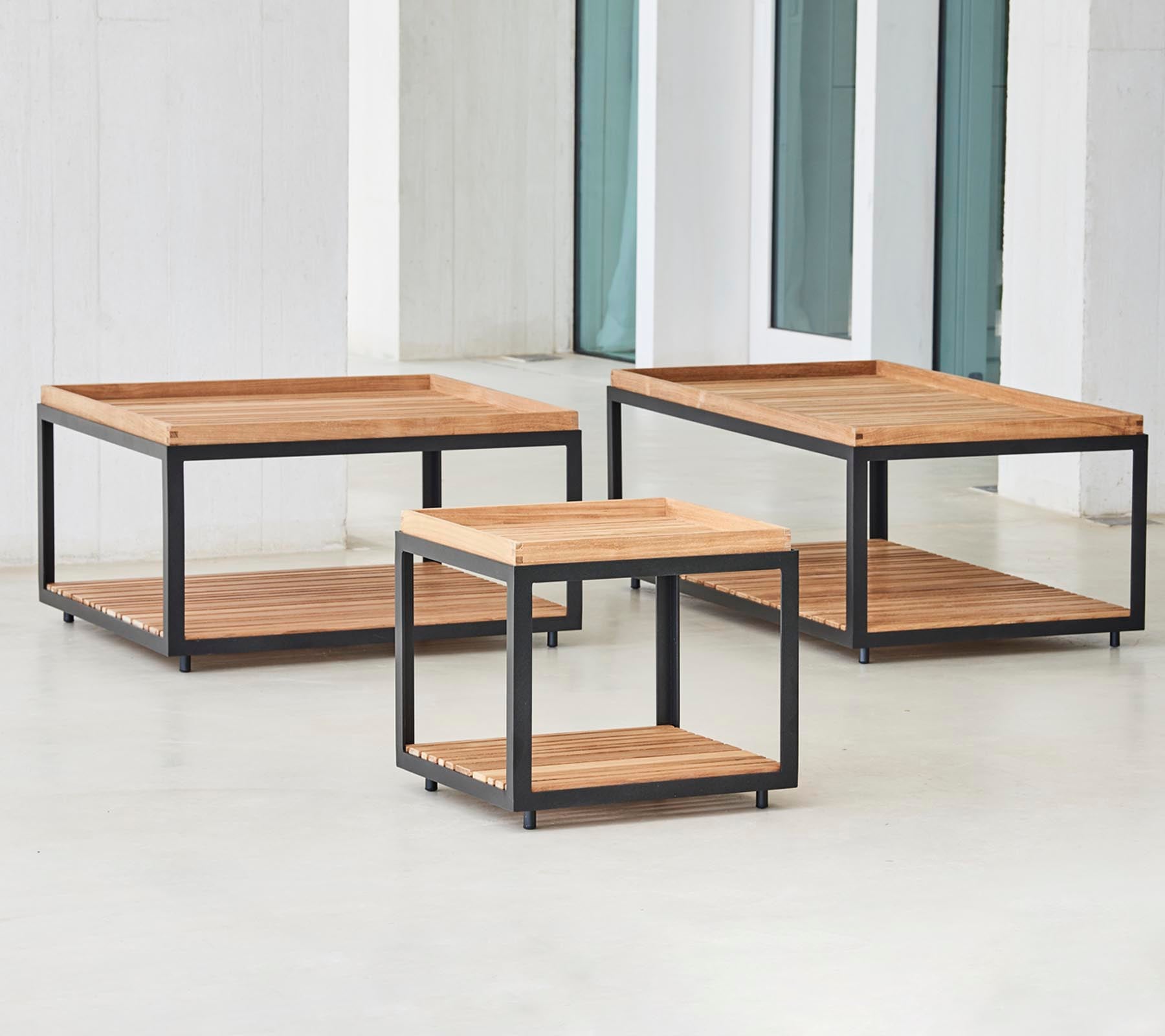Three stylish wooden coffee tables with black metal frames in varying sizes, featuring open lower shelves for storage and display.