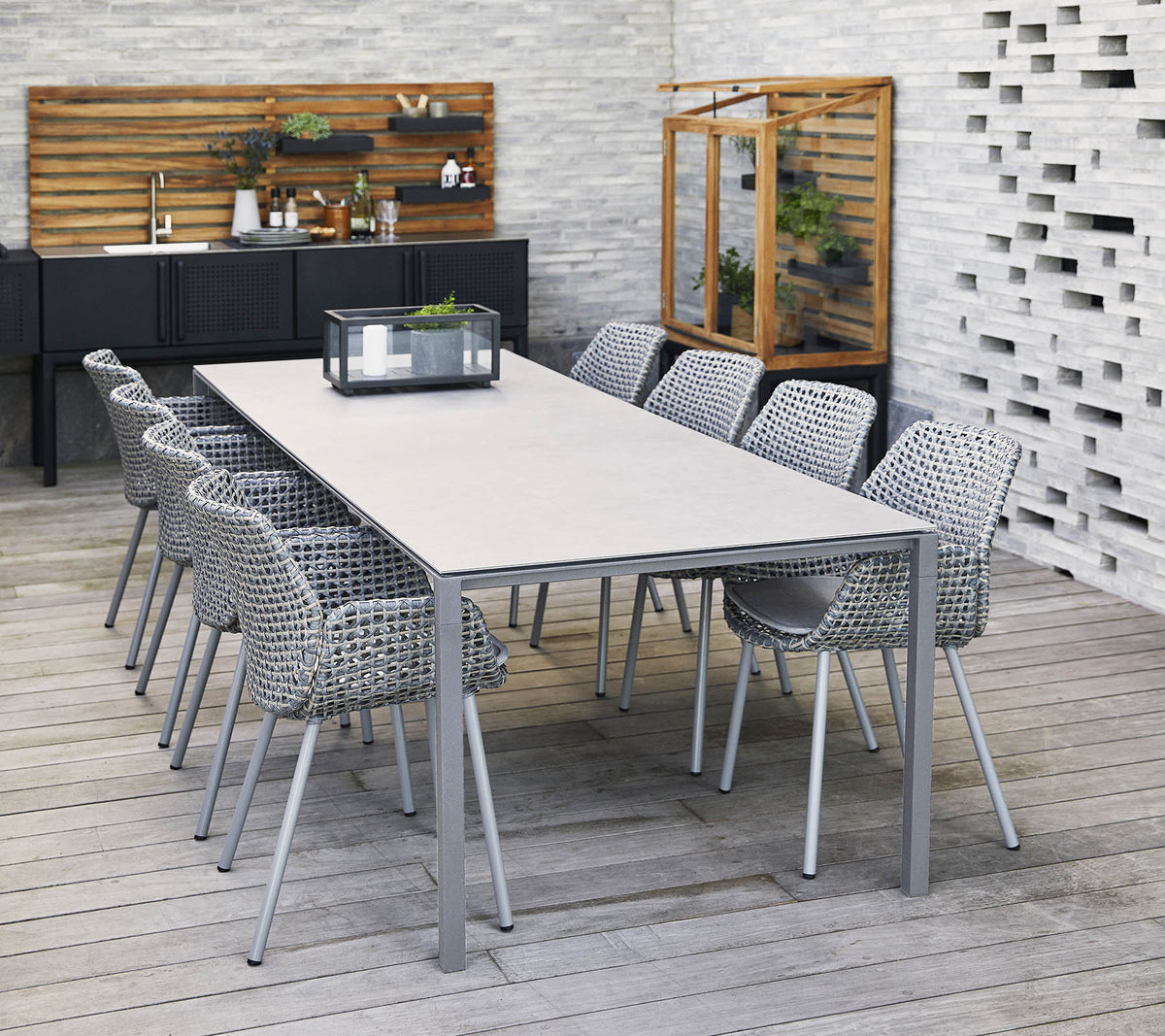 A stylish long table surrounded by woven chairs, with a centerpiece and decorative elements in a contemporary setting.
