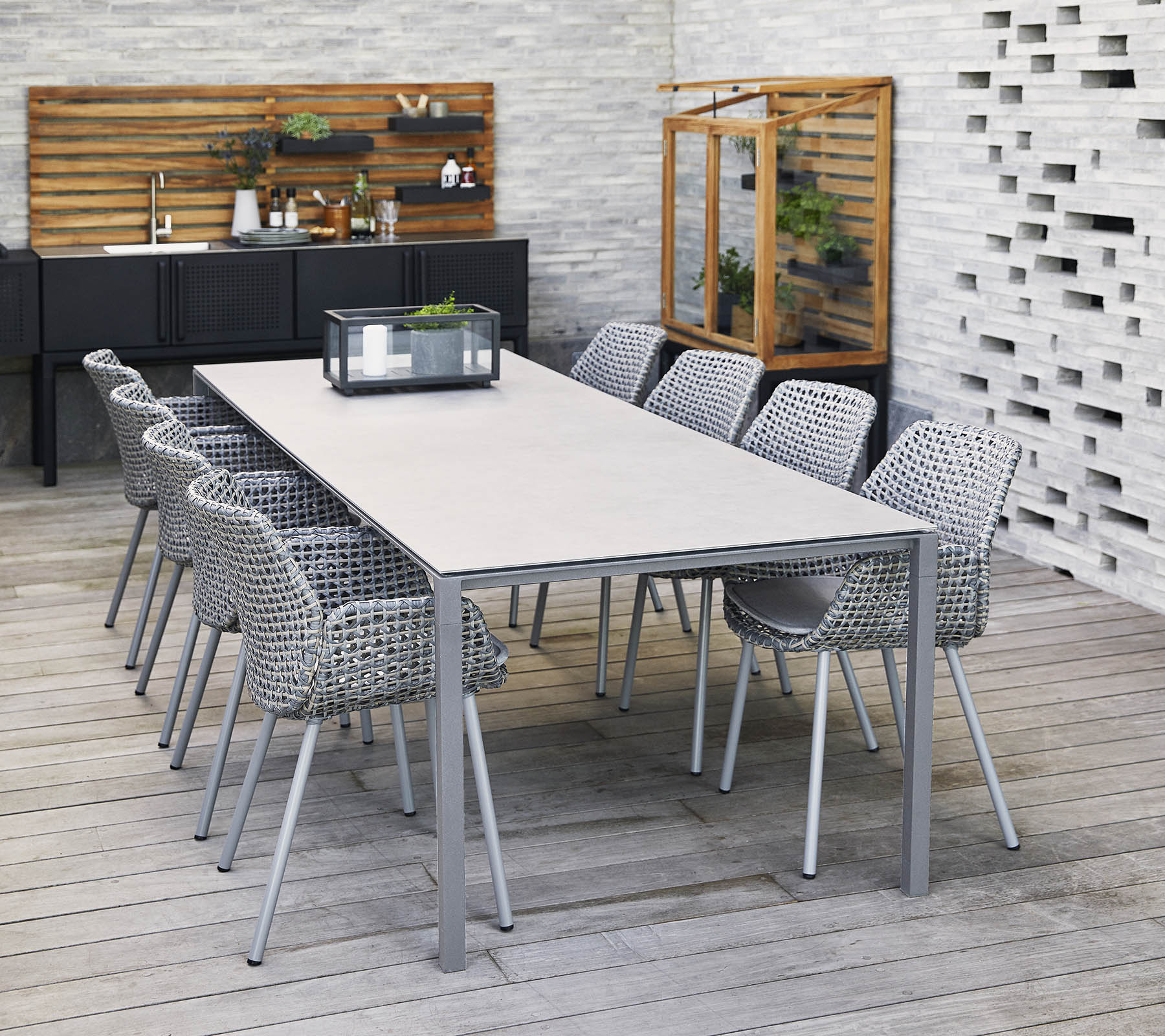 A stylish long table surrounded by woven chairs, with a centerpiece and decorative elements in a contemporary setting.