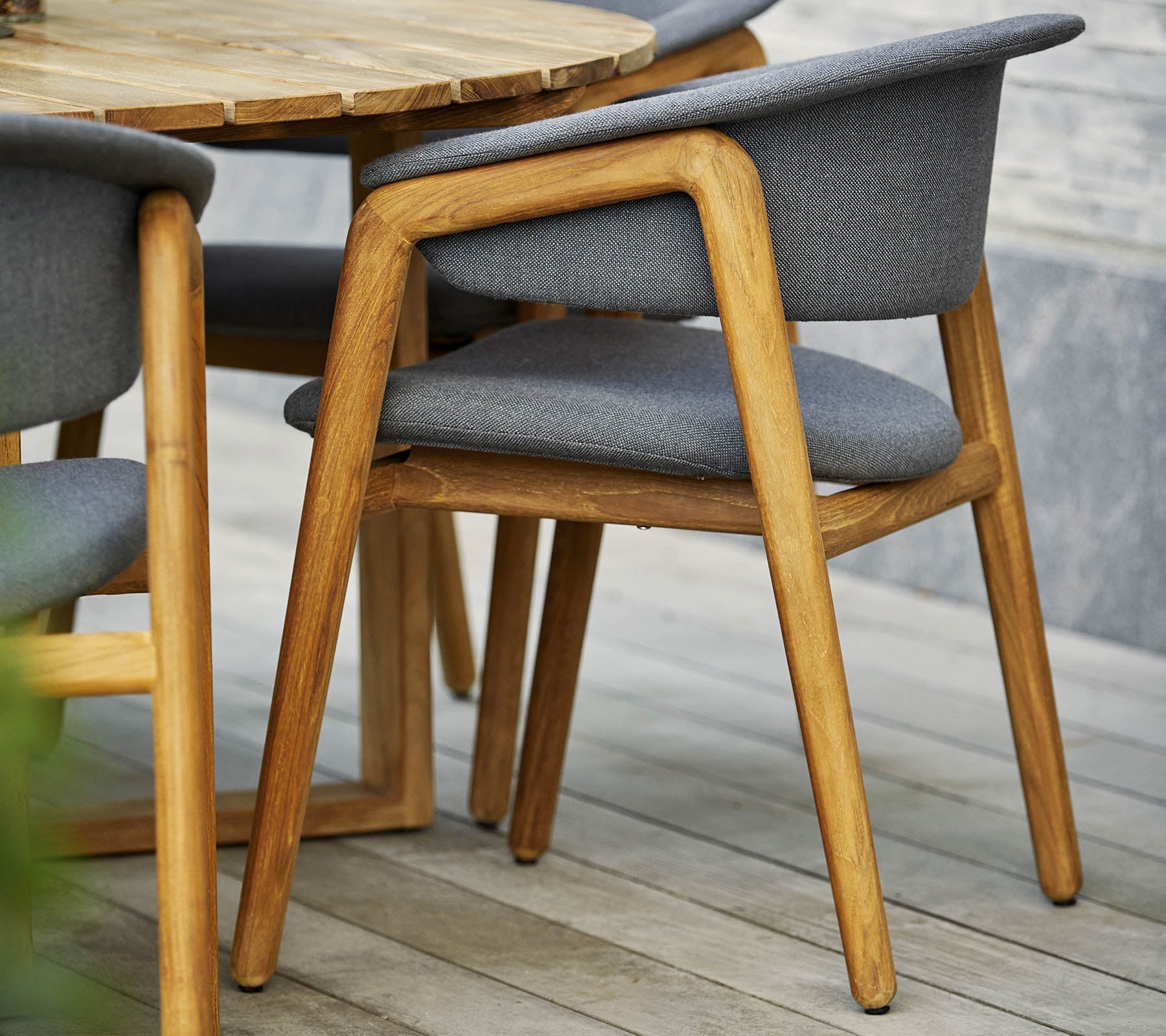 Stylish wooden chair with gray upholstered seat and backrest, paired with a round table set in a contemporary design.