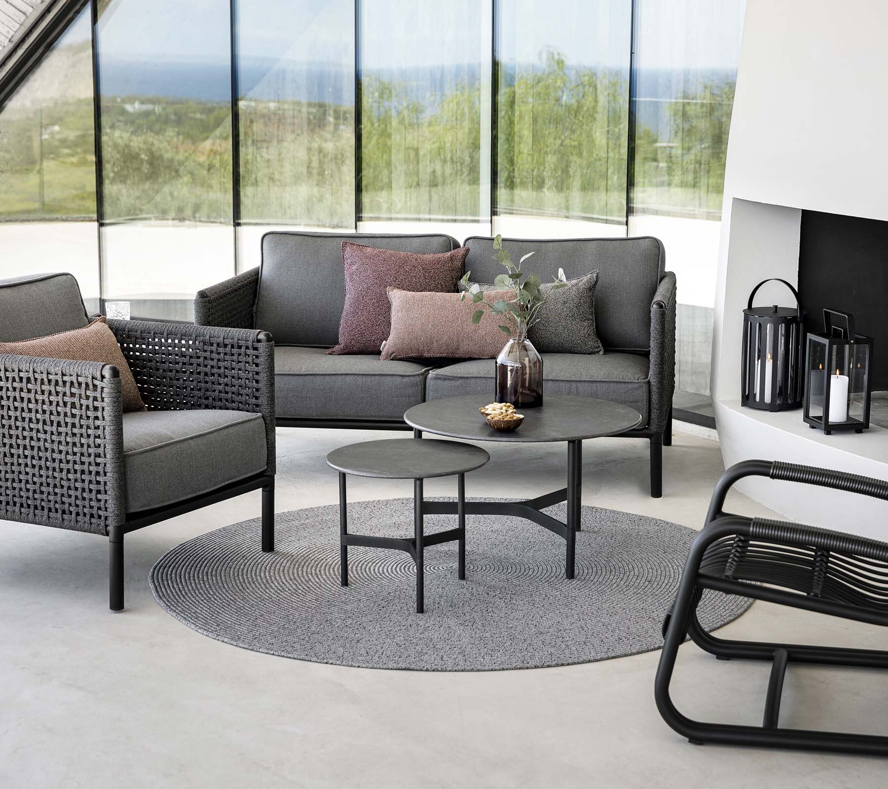Stylish seating area featuring a gray sofa with cushions, round coffee table, and accent chairs on a circular rug. Natural light enhances the ambiance.