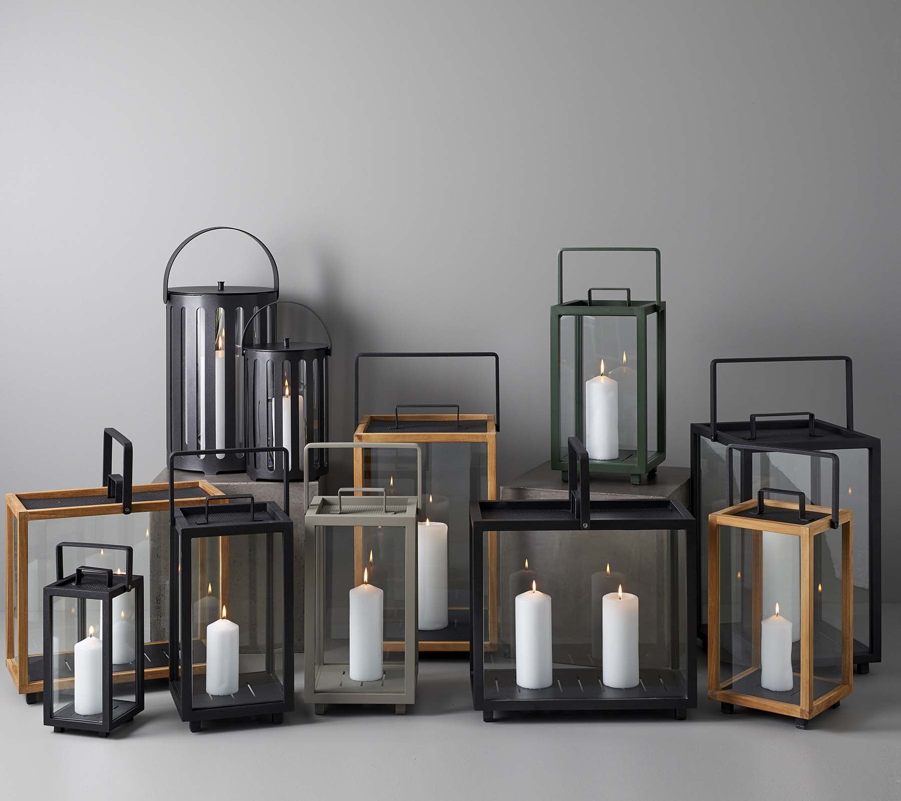 A collection of elegant lanterns in various sizes and styles, featuring candles inside, arranged together on a neutral background.