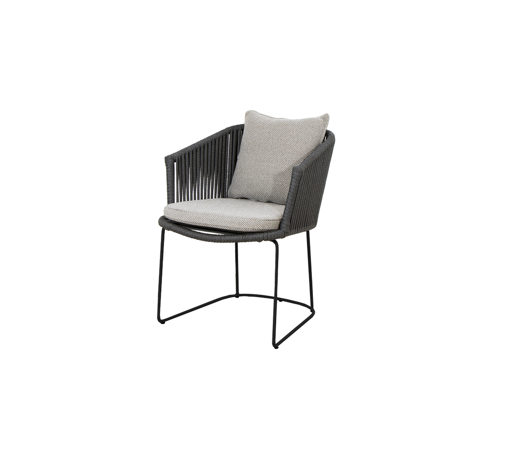 A modern chair with a wicker design and a soft cushion, featuring a sleek metal base for support.