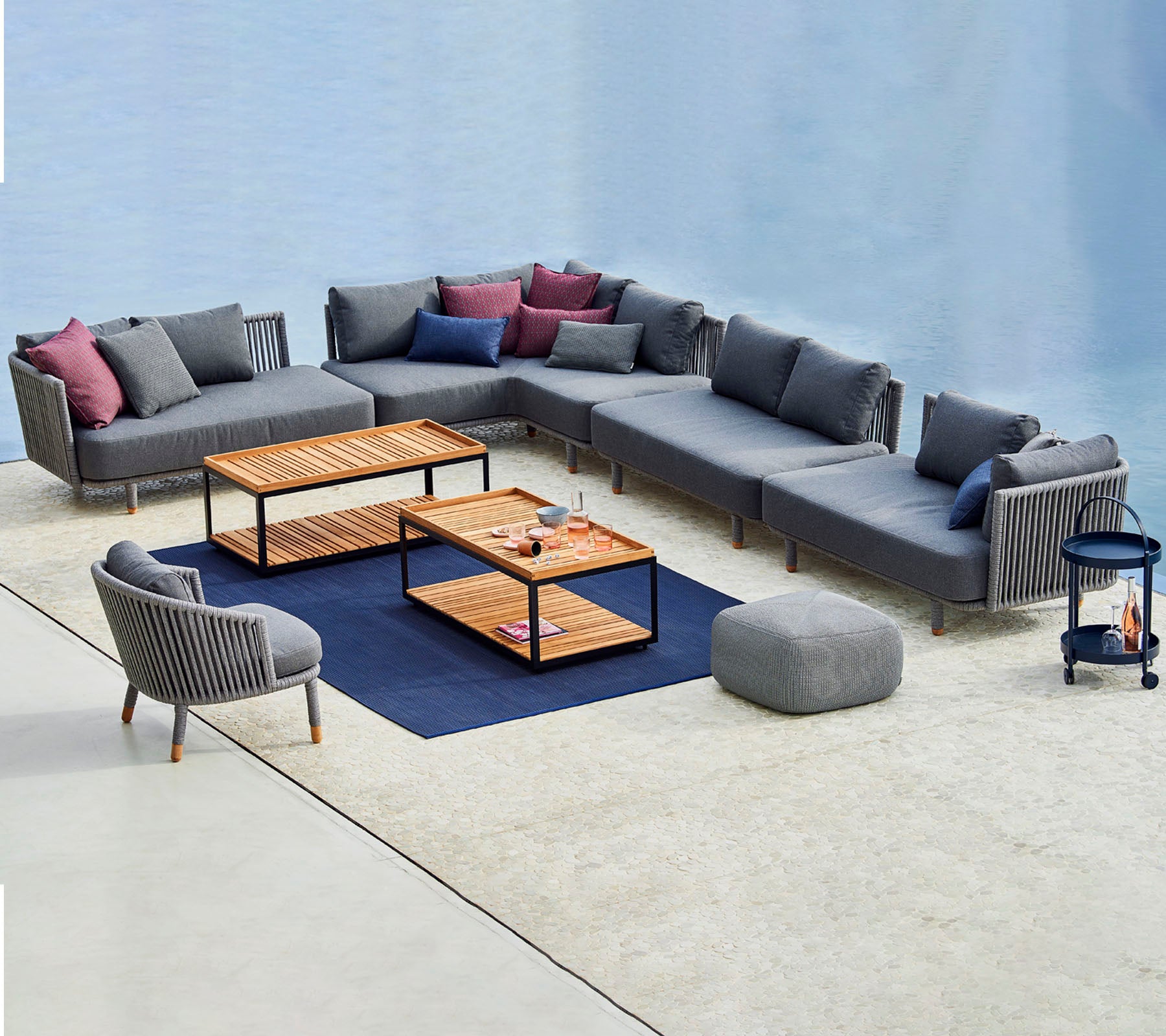 Contemporary seating arrangement featuring a modular gray sofa with colorful cushions, coffee tables, and a matching accent chair.
