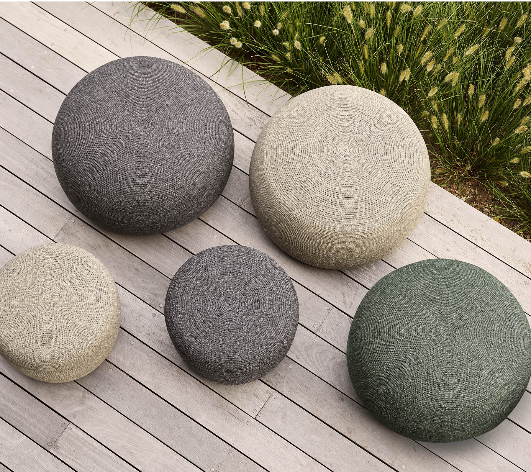 A set of five round poufs in various sizes and colors, featuring textured surfaces that add a modern touch to any space.