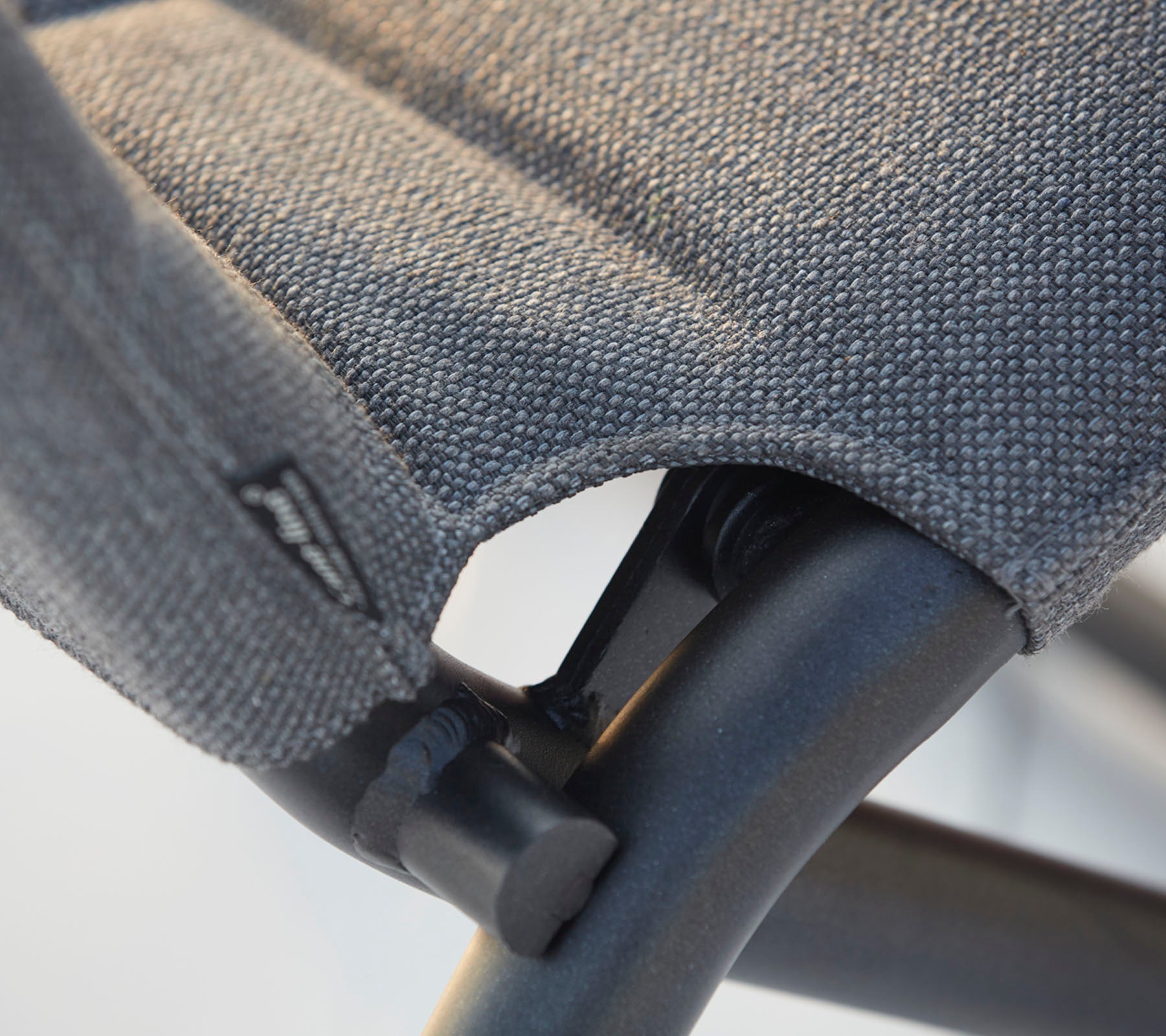 Close-up of a chair's textured fabric seat and sturdy black frame, highlighting the stitching and design details.