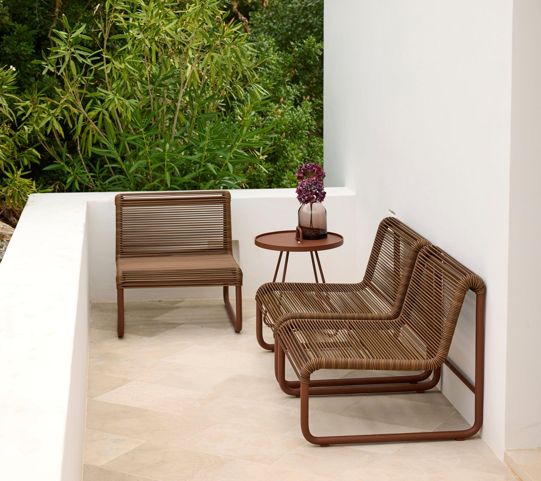 Modern outdoor lounge area featuring brown chairs and a round table.