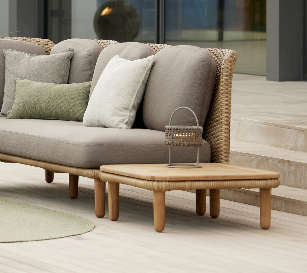 Stylish arch coffee table with a teak top alongside cushions on a modern sofa, complemented by a decorative Illusion lamp.