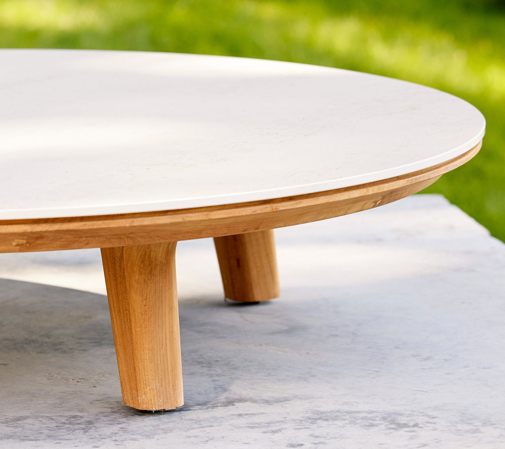 Close-up of a circular coffee table featuring a smooth surface and wooden legs, highlighting its elegant design and craftsmanship.
