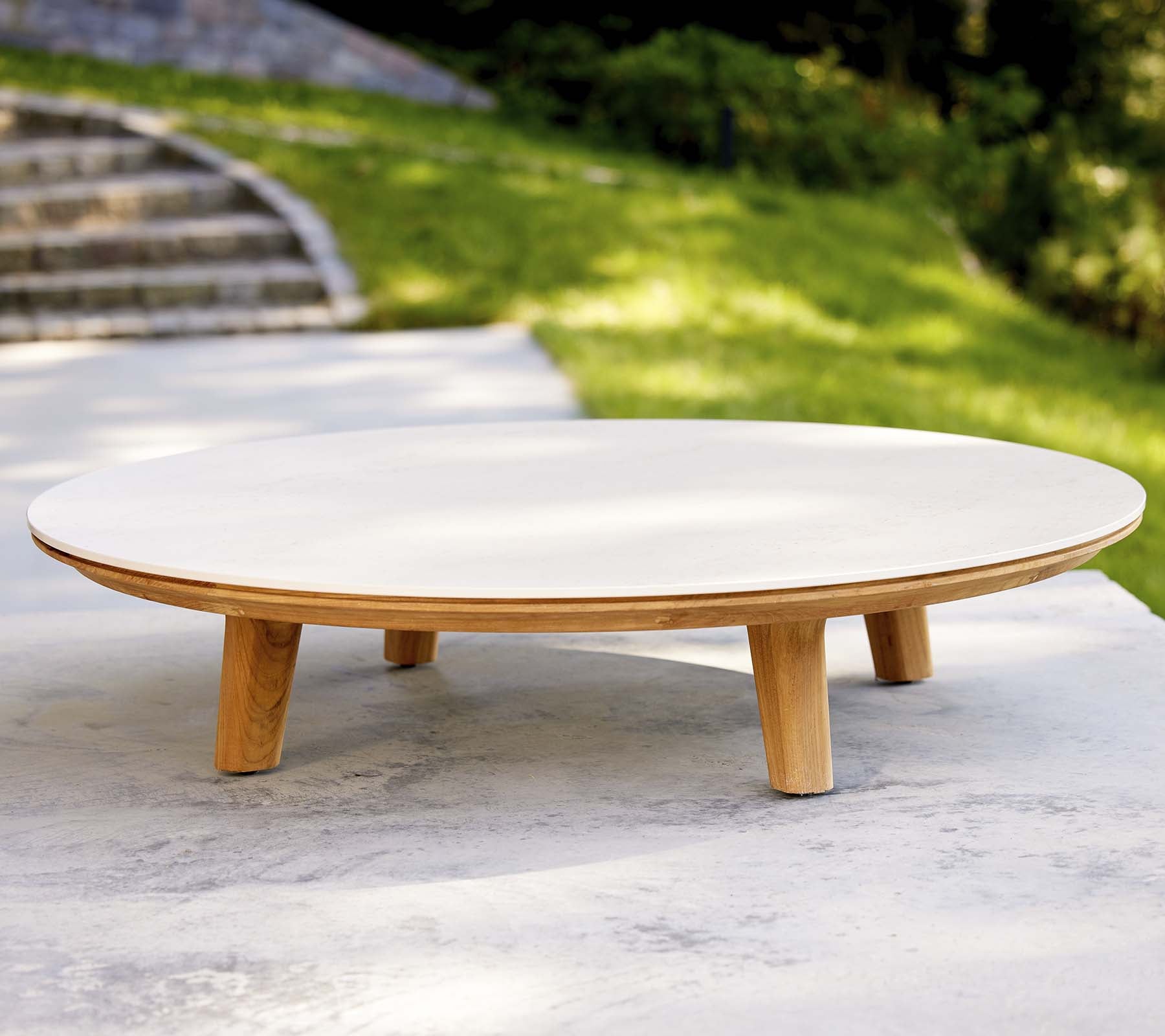 Modern round coffee table with a smooth surface and wooden legs, featuring a minimalist design suitable for various settings.