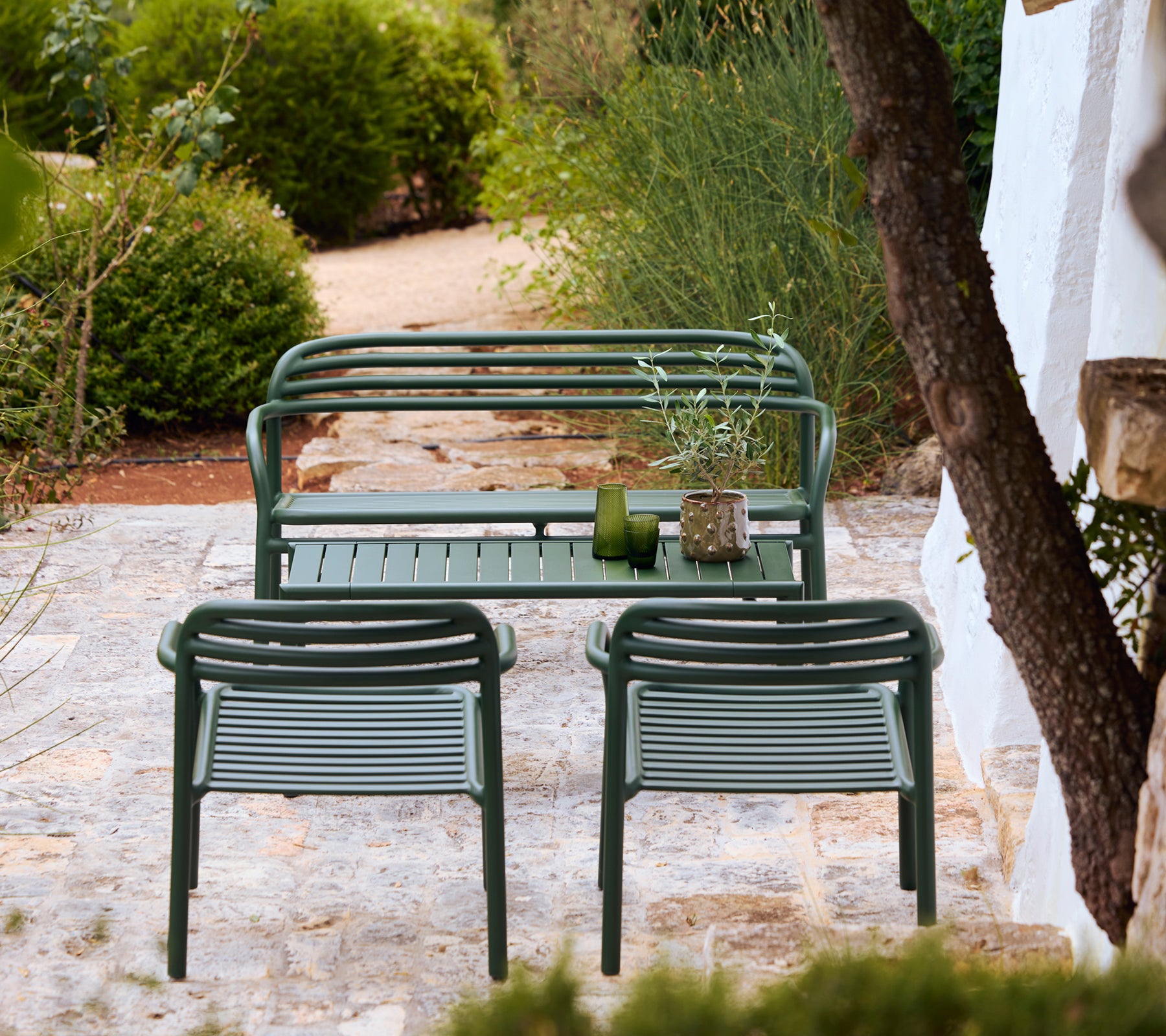 Modern green bench and chairs in a stylish outdoor lounge setting.