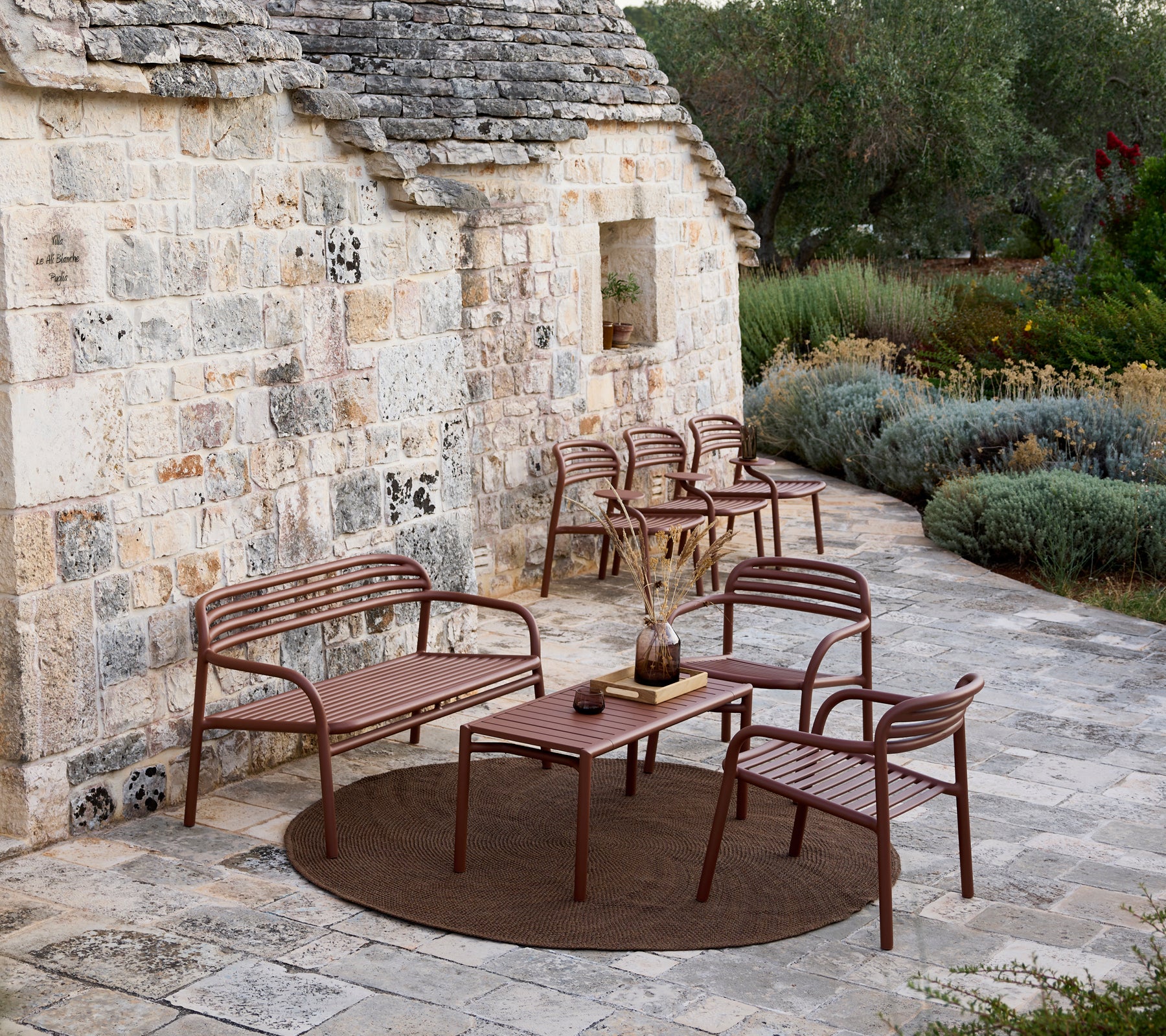 Brown outdoor sofa, chairs, and table set in a modern lounge area.