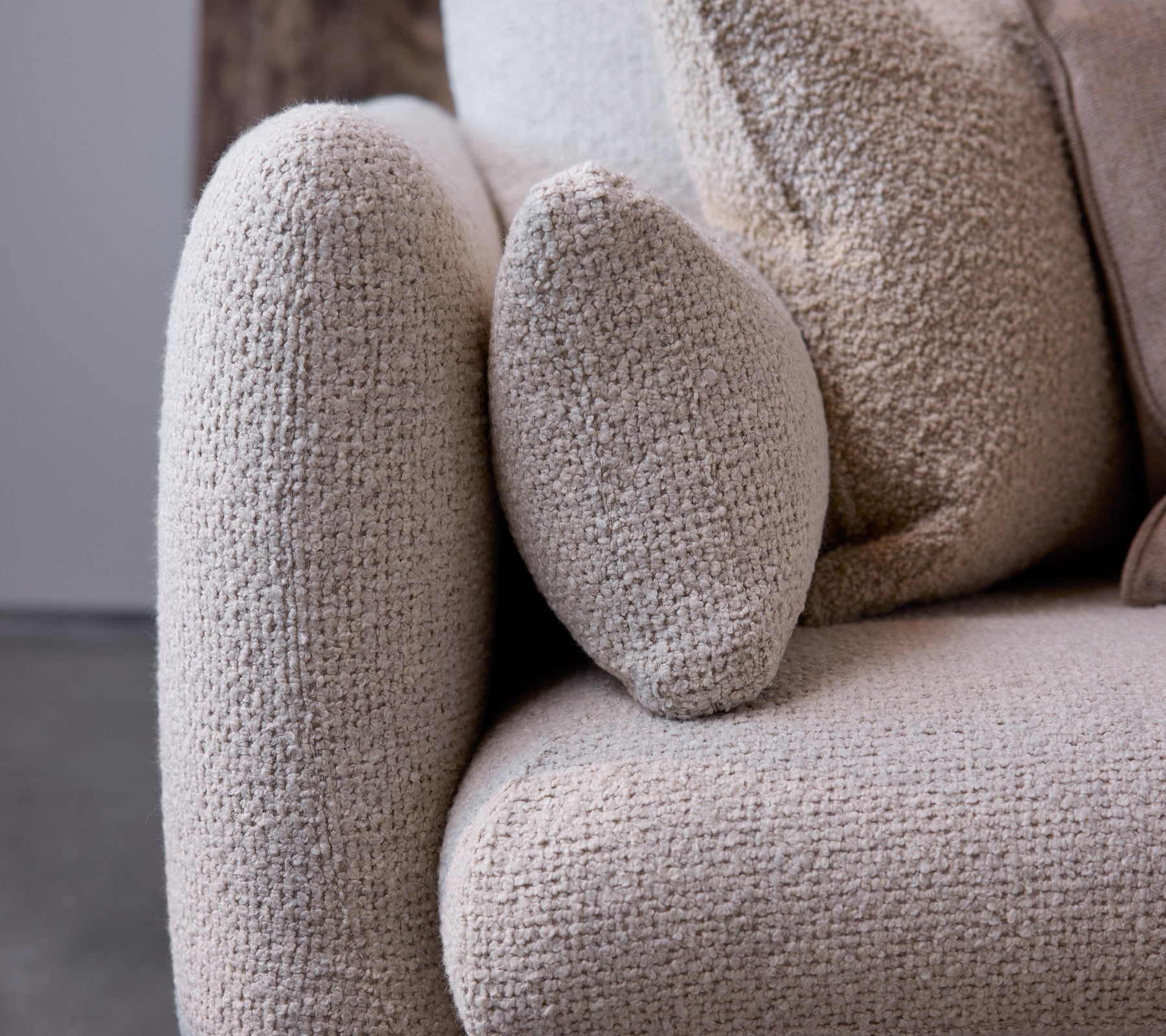 Close-up of the armrest of a Bloom sofa in a sand flair texture, showcasing a rounded design and soft, cozy fabric.