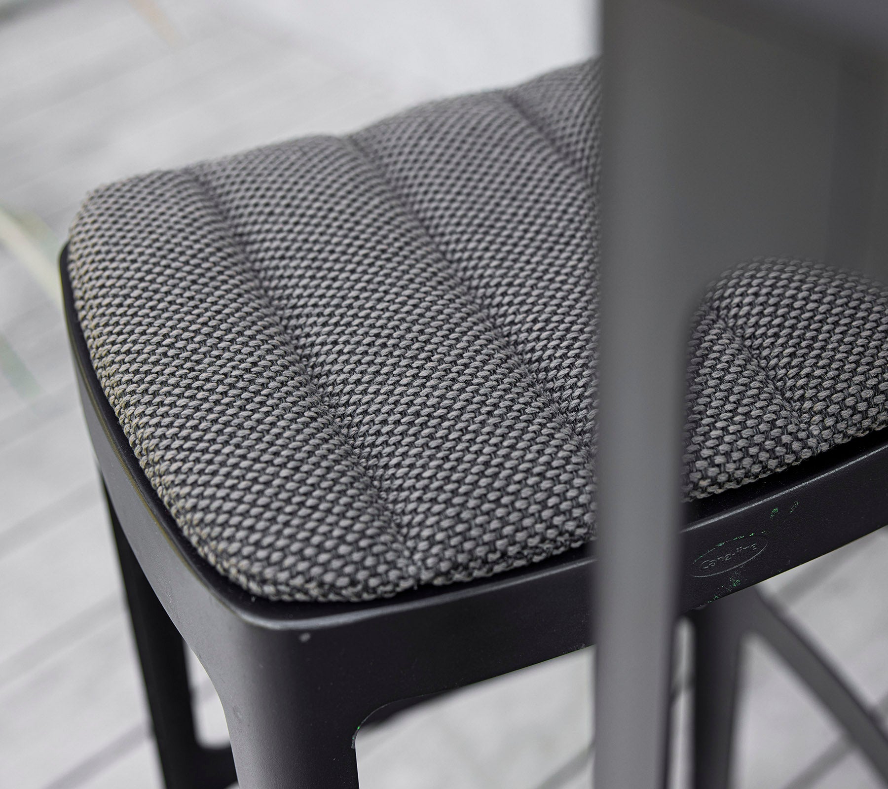 Close-up of a textured black chair seat featuring a quilted design, showcasing modern craftsmanship and attention to detail.