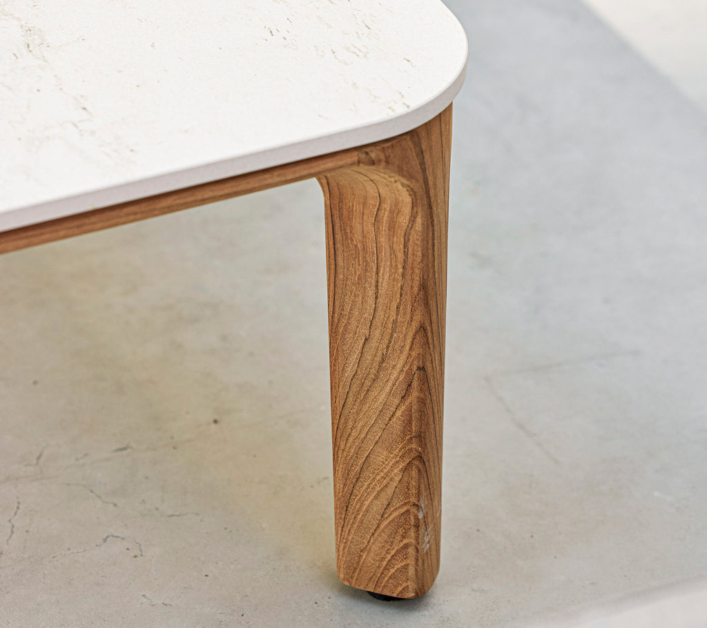 A close-up of a table featuring a textured wooden leg and a smooth, white tabletop. Elegant and modern design elements are highlighted.