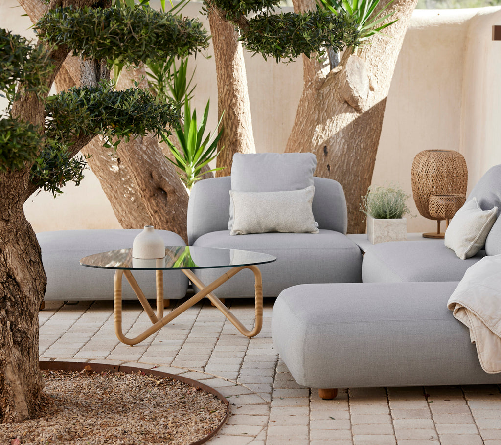 Modern lounge area featuring a grey sofa, white pillow, and glass coffee table.