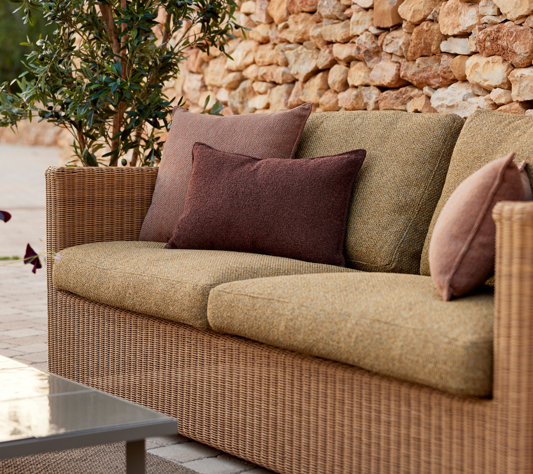 Modern beige sofa with purple and brown cushions in a lounge setting.