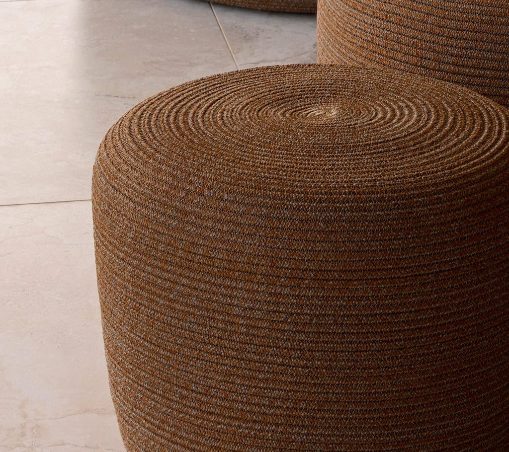 Small umber brown circle footstool with a textured woven surface, providing a stylish accent for seating or decoration.
