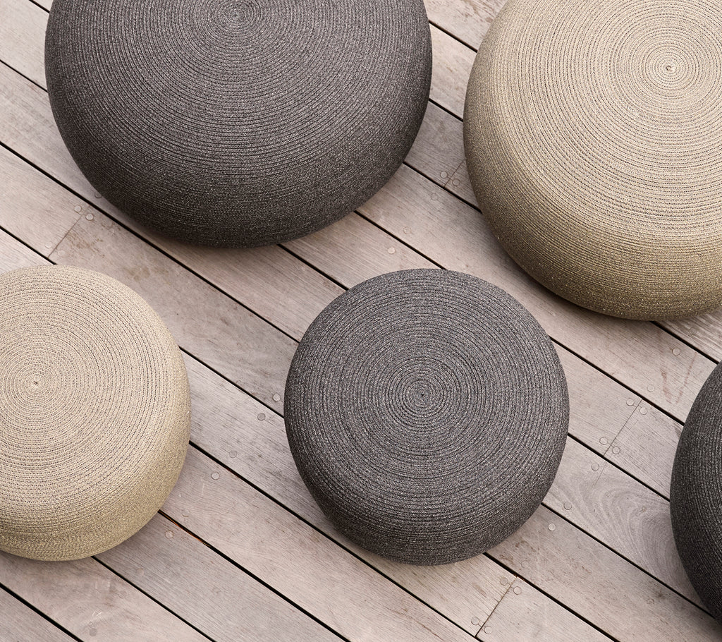 A collection of round footstools in varying sizes and neutral colors arranged on a wooden surface.