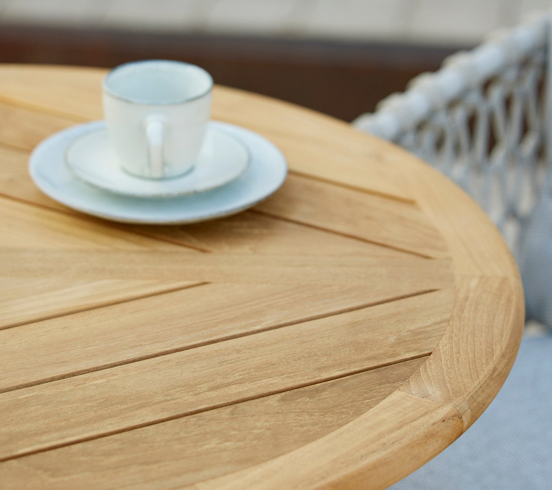 A wooden table with a coffee cup and saucer on top, showcasing a minimalist and inviting café setting.