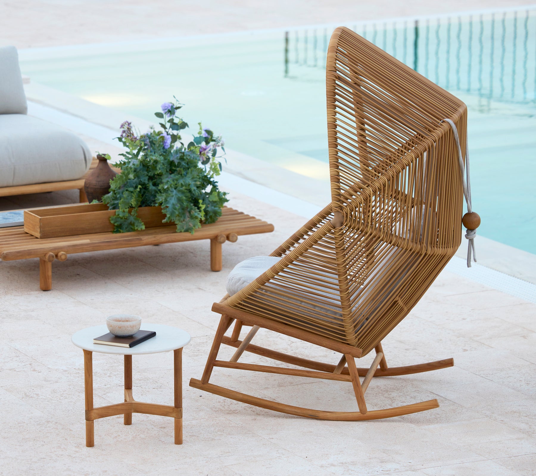 A stylish Hive rocking chair beside a Twist coffee table and a Sticks coffee table, complemented by a potted plant.