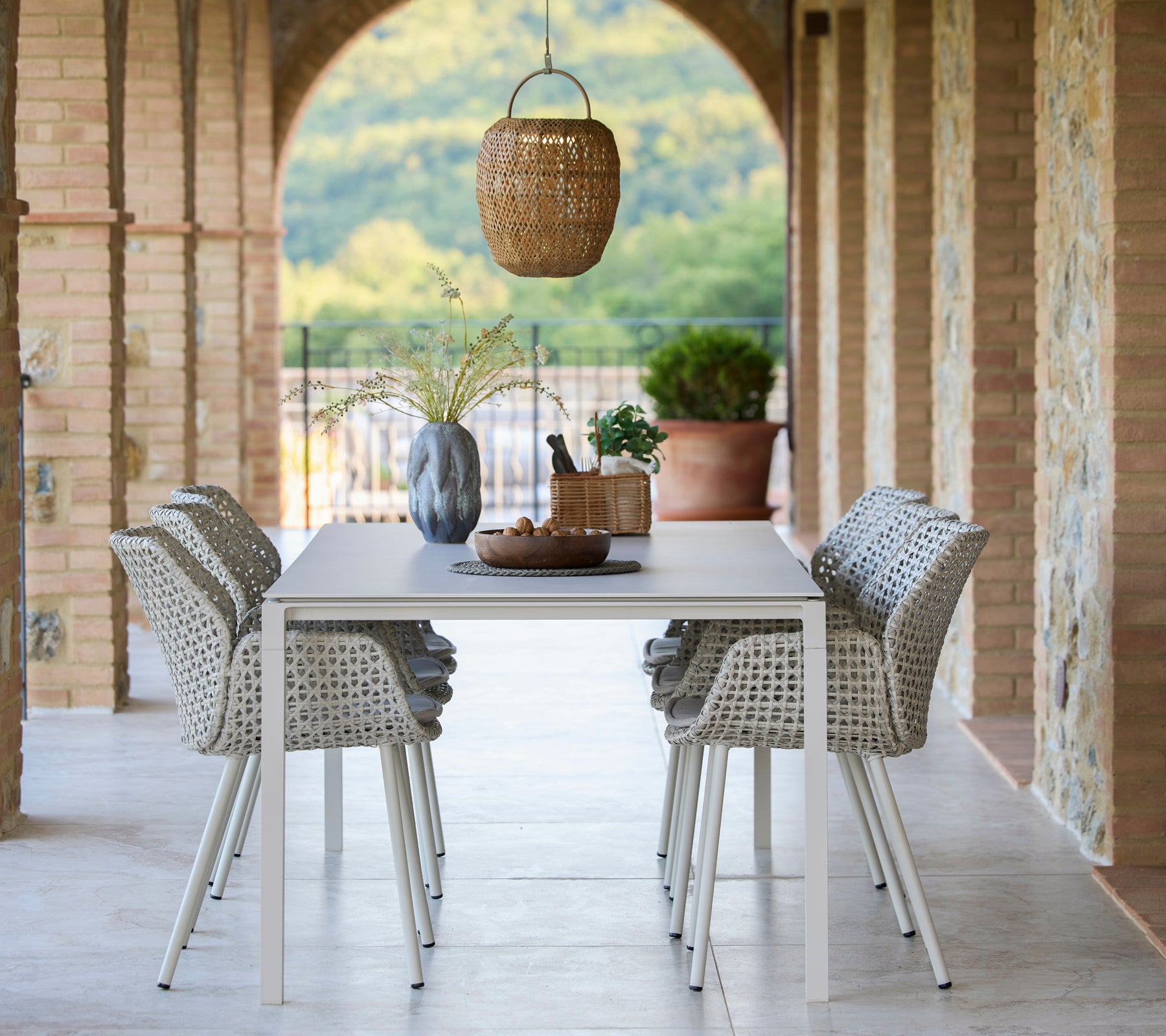 A dining setting featuring a Pure table surrounded by Vibe dining chairs, enhanced by a hanging Illusion Glow lamp and decorative elements.