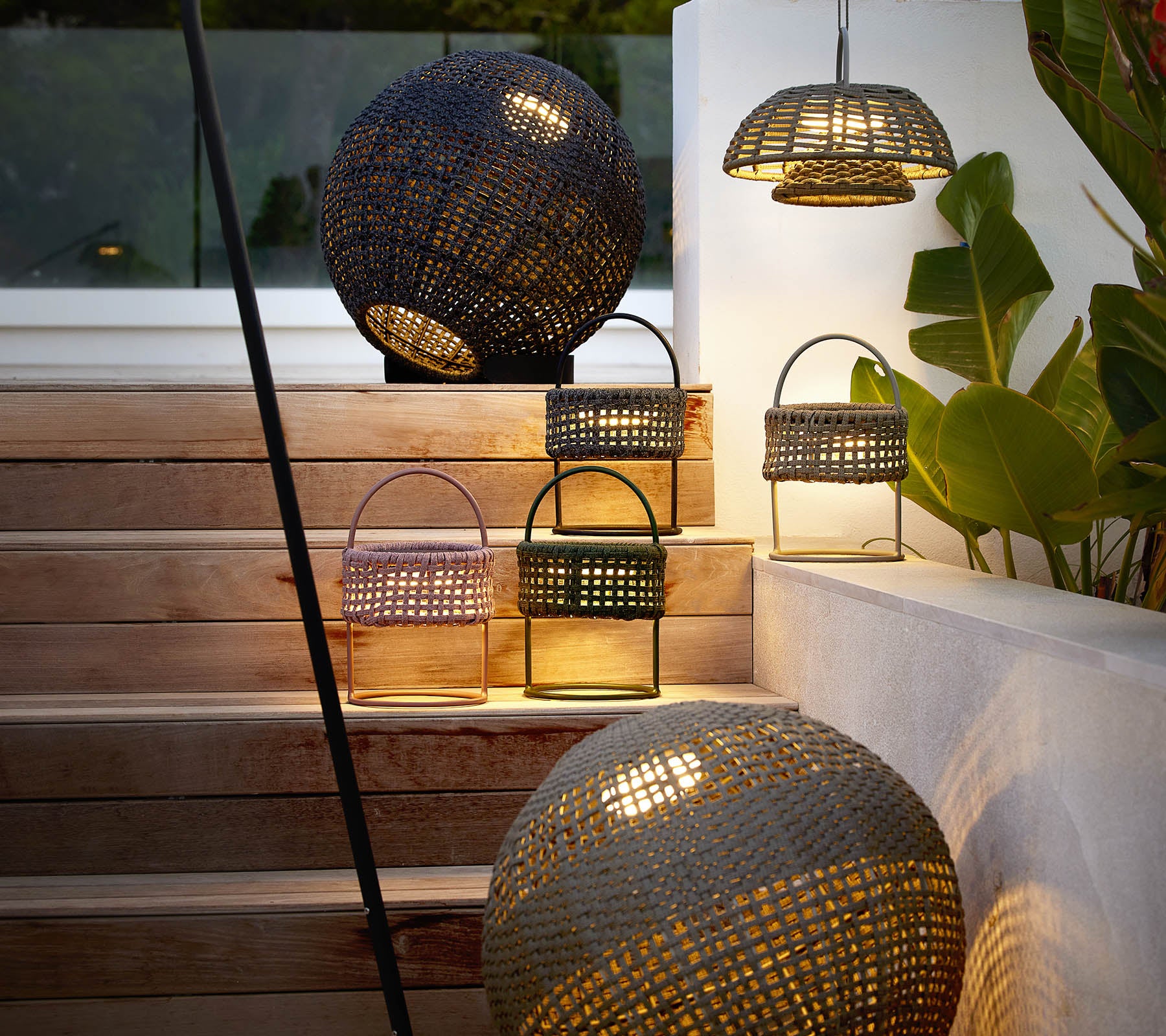 A collection of stylish illusion lamps in various shapes, casting a warm, inviting glow amidst decorative greenery.