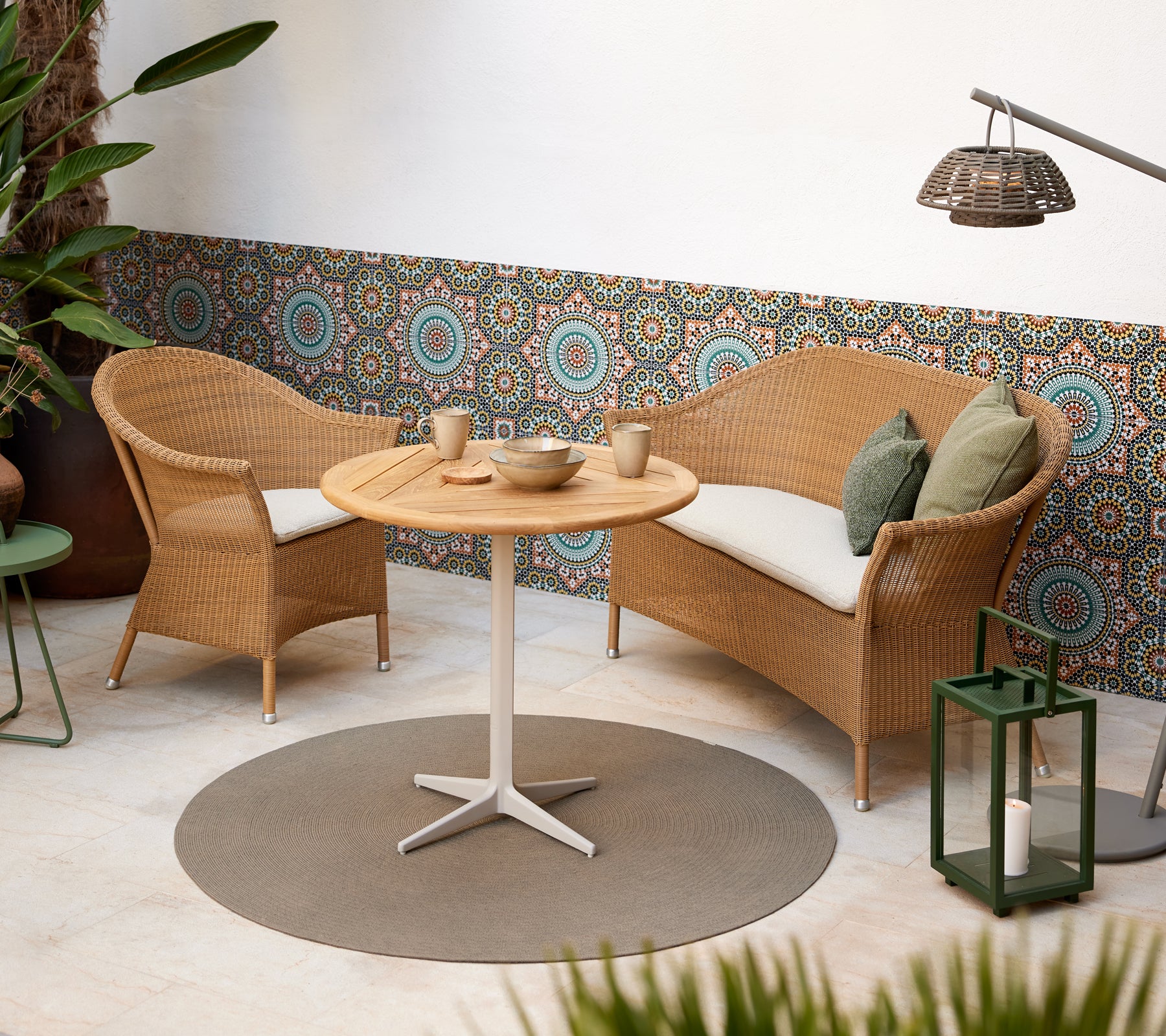 A cozy seating area featuring woven chairs and a round table, complemented by vibrant circular patterns in the background.