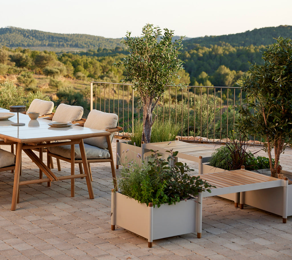 A stylish seating area featuring a table, comfortable chairs, and planters filled with greenery, enhancing a serene landscape.