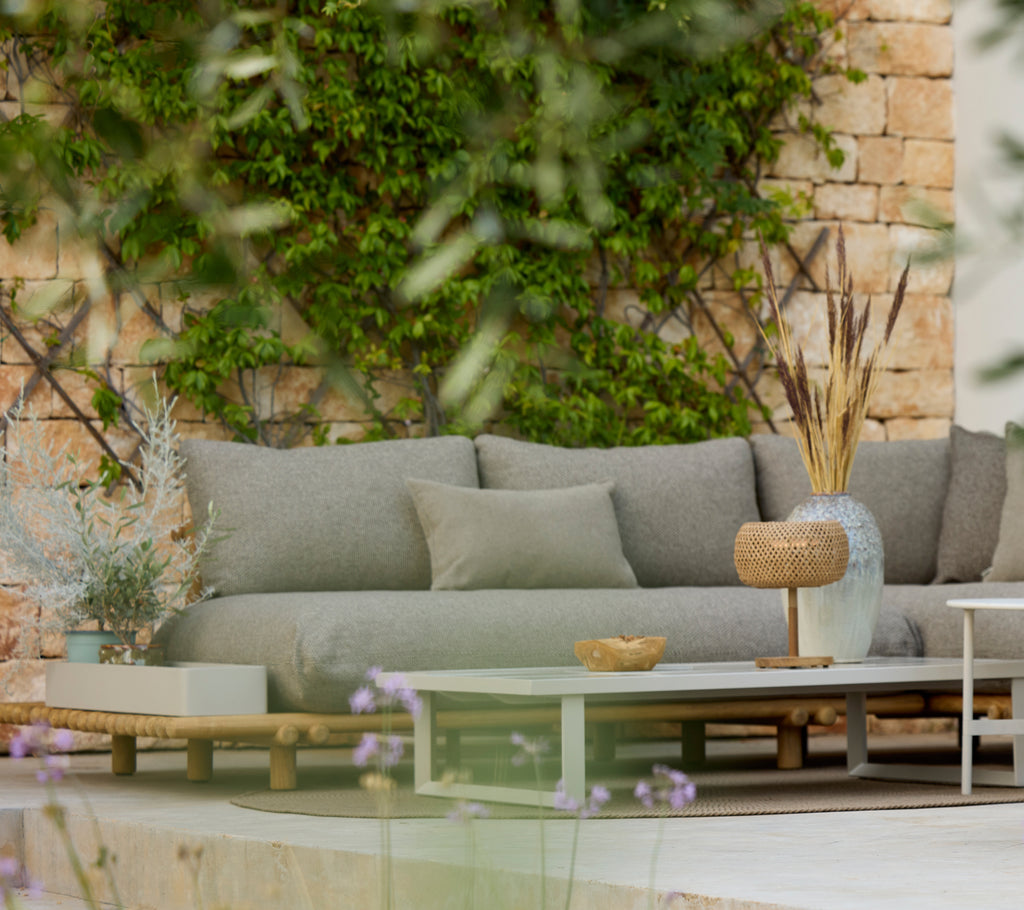 Modern grey sofa with a wooden table in a stylish outdoor lounge area.